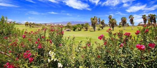 uma vista para um campo de golfe com flores e palmeiras em El Dorado Sun Las Américas em Playa de las Americas