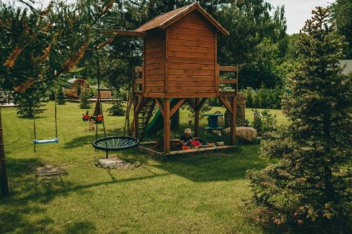 a wooden play house with a swing in a yard at HORBACZÓWKA in Czerwonki