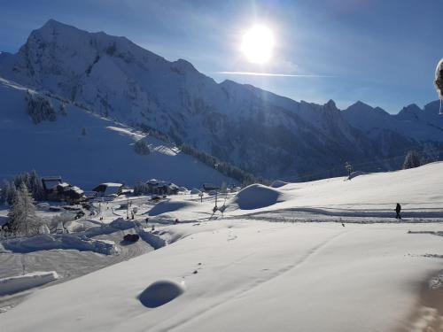 une montagne enneigée avec le soleil en arrière-plan dans l'établissement LES FEUDIERES, à Manigod