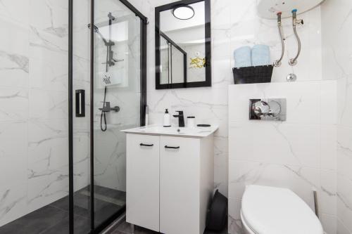 a white bathroom with a sink and a shower at Apartments Stinice in Gradac