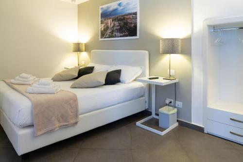 a bedroom with a white bed and a side table at Le Stanze di Piazza Cairoli in Messina
