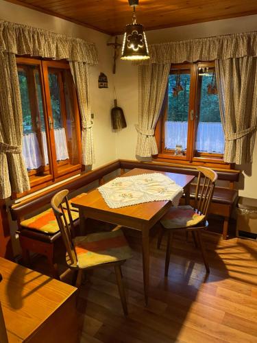 a dining room with a table and chairs and windows at Hiša pod Rogatcem in Luče