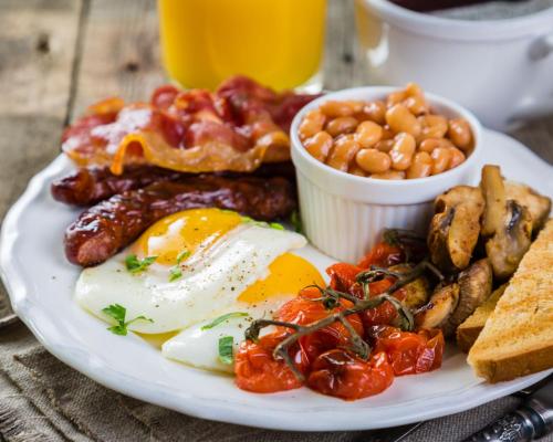 Un plato de desayuno con huevos, salchichas, frijoles y tostadas. en Eype's Mouth Country Hotel, en Bridport