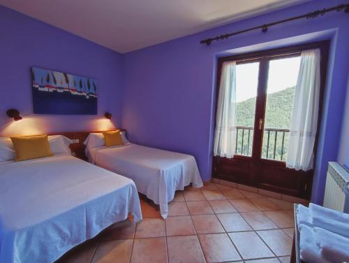 a blue room with two beds and a window at Hotel Rural LAbadia de Sieste in Sieste