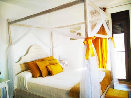 a bedroom with a white canopy bed with yellow pillows at Escapada Romantica con Jacuzzi y vistas al Castillo de Trevejo in Villamiel