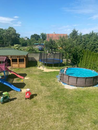 un patio trasero con piscina y equipo de juegos en Dom Goscinny Luna en Stegna
