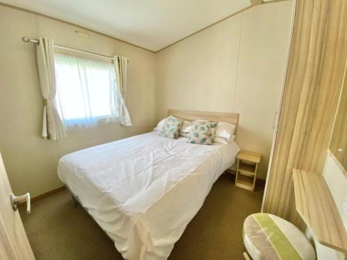 a bedroom with a white bed with a window at Waterside Holiday Park in Goodrington