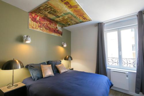 une chambre avec un lit bleu et une fenêtre dans l'établissement Le Grunge, T2 hypercentre chic et cosy, Wifi par SOVALFI, à Saint-Étienne