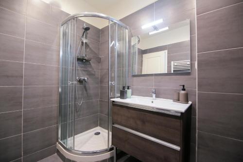 La salle de bains est pourvue d'une douche, d'un lavabo et d'un miroir. dans l'établissement Le Grunge, T2 hypercentre chic et cosy, Wifi par SOVALFI, à Saint-Étienne