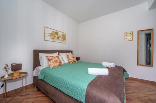 ein Schlafzimmer mit einem Bett mit einer grünen Bettdecke in der Unterkunft Apartments Fortunella in Petrovac na Moru