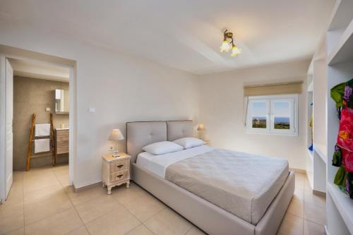ein weißes Schlafzimmer mit einem Bett und einem Fenster in der Unterkunft George Apartments2 in Vóthon