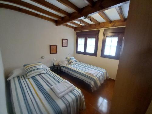 two beds in a room with two windows at La Casina de Póo de LLanes in Po