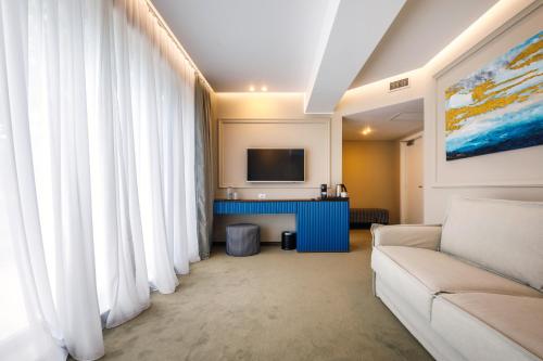 a living room with white curtains and a couch at Onal Boutique Hotelier in Mamaia