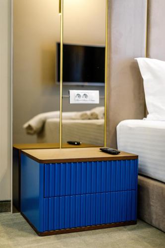 a blue nightstand with a mirror next to a bed at Onal Boutique Hotelier in Mamaia