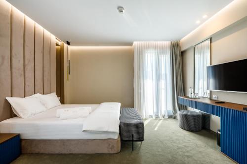 a hotel room with a bed and a flat screen tv at Onal Boutique Hotelier in Mamaia