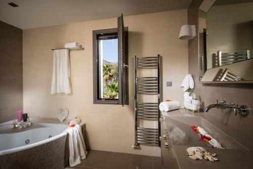 a bathroom with a tub and a sink and a window at Villa Belamar in Hersonissos