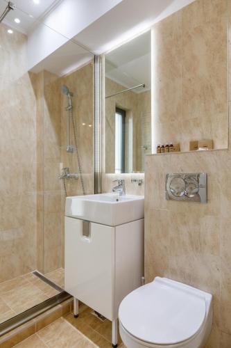 a bathroom with a toilet and a sink and a mirror at Onal Boutique Hotelier in Mamaia
