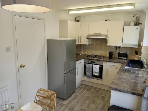 a kitchen with a stainless steel refrigerator and white cabinets at Stamford Redcot Gardens Stylish 2 bed Family town house with parking in Lincolnshire