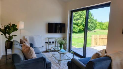 Balsham的住宿－Finest Retreats - Blackbarn Wood，客厅配有2张蓝色沙发和滑动玻璃门