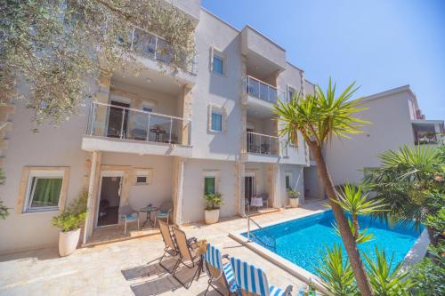 ein Apartment mit einem Pool vor einem Gebäude in der Unterkunft Apartments Fortunella in Petrovac na Moru