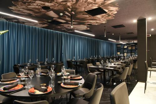 a dining room with tables and chairs and blue curtains at DEMSI Palace Hotel & Restaurant in Foggia