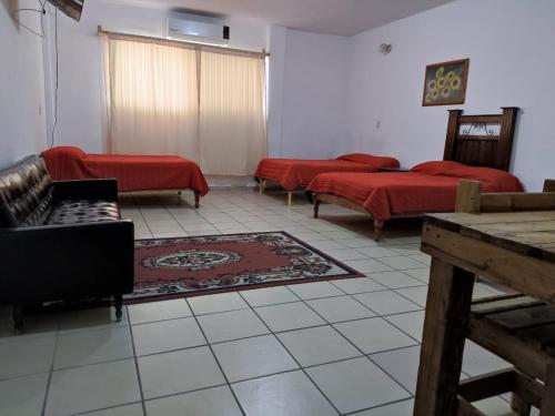 a living room with three beds and red sheets at HOTEL PREMIER RIOVERDE in Río Verde