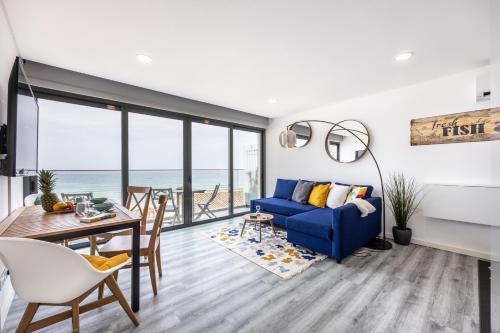 ein Wohnzimmer mit einem blauen Sofa und einem Tisch in der Unterkunft Frontline Seaview Apartment in Budens