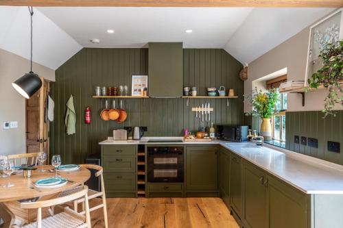 een keuken met groene kasten en een houten tafel bij Crabtree Farm - South Stable in Ashford
