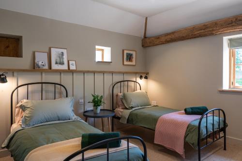 Cette chambre comprend 2 lits, une table et une fenêtre. dans l'établissement Crabtree Farm - South Stable, à Ashford