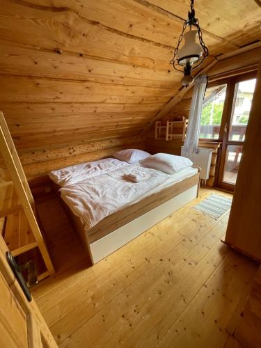 a bedroom with a bed in a wooden cabin at TRINITY Log Cabin Wellness resort in Štrba