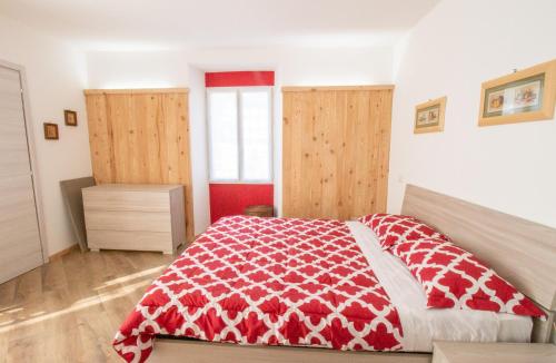 a bedroom with a bed with a red and white blanket at Il tulipano della Valle Soana in Ronco Canavese