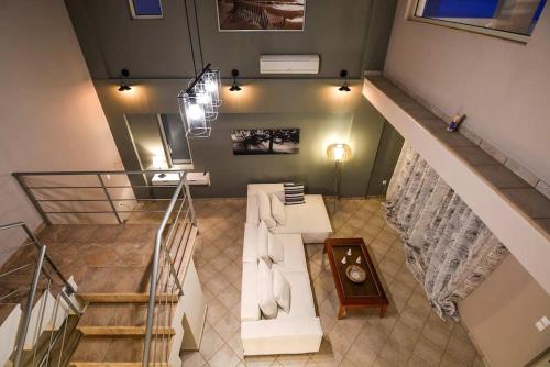 a living room with a white couch and a staircase at Aigli Luxurious Villa in Káto Pitsá