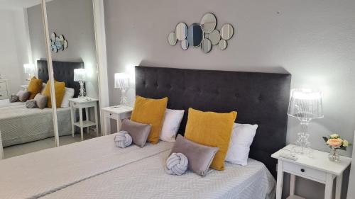 een slaapkamer met een groot bed met kussens en spiegels bij Benalmadena JUPITER - Delux 1Bedroom Apartment in Benalmádena