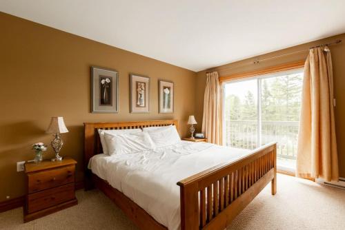 - une chambre avec un grand lit et une fenêtre dans l'établissement Serenity Peaks Lodge by InstantSuites-LaBete Golf, à Mont-Tremblant