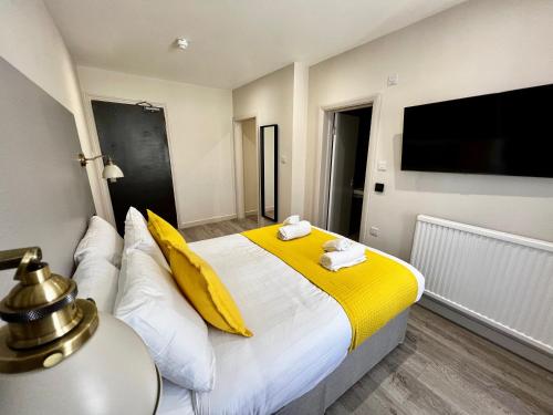 a bedroom with a bed with yellow and white sheets at Pearl & Pebbles Eastbourne in Eastbourne