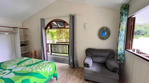 een slaapkamer met een bed en een stoel en een balkon bij Matatia Lodge in Punaauia