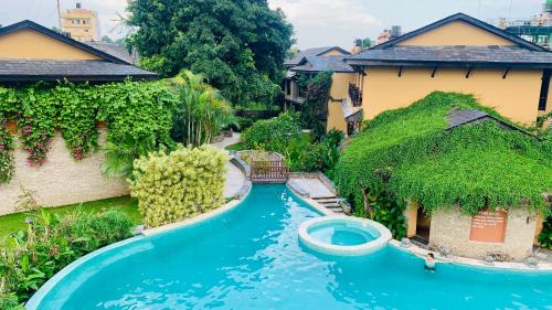 a pool in the middle of a yard with houses at Temple Tree Resort & Spa in Pokhara