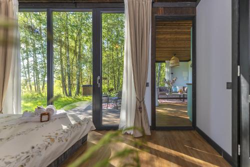 1 dormitorio con 1 cama y puertas correderas de cristal en Modern and specious riverside cabin with hot tub en Čiobiškis