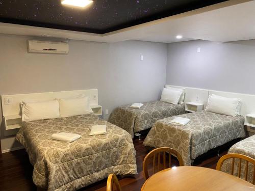 um quarto com três camas e uma mesa e cadeiras em Hotel Westphal em Pelotas