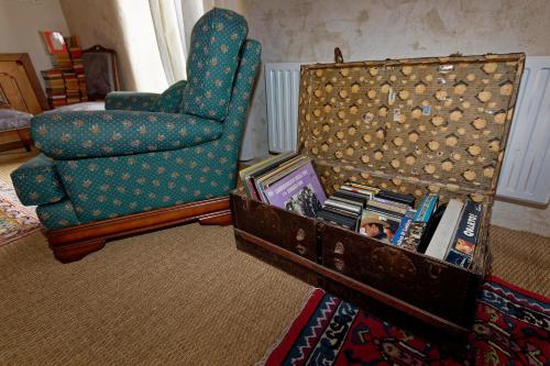 a living room with a chair and a table with books at LE MOULIN DU COUFFON in Kerlouan
