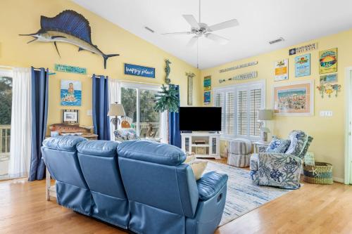 a living room with blue chairs and a tv at On Island Time in Atlantic Beach