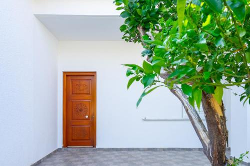 a white building with a wooden door and a tree at panorama view apartment in Sitia