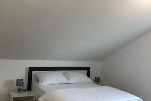 a bedroom with a bed with white sheets and pillows at Vikendica Bruše in Jaklići