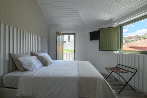 a bedroom with a white bed and a window at Casa da Torre in Amarante
