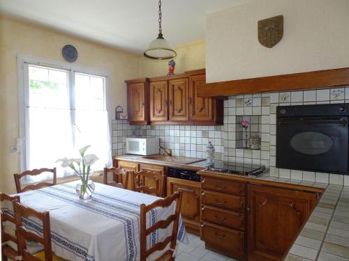 une cuisine avec des placards en bois et une table avec un chiffon de table blanc dans l'établissement Holiday Home in Guerlesquin near Lake, à Guerlesquin