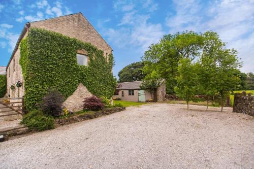 een met klimop overdekt huis met een grindoprit bij The Old Barn in Buxton