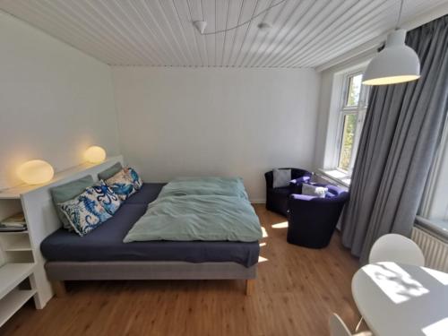 ein Schlafzimmer mit einem Bett, einem Stuhl und einem Tisch in der Unterkunft The Cherry Apartment - 'Den Gule Svane' Guest House near Rønne & Beach in Rønne