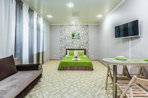 a bedroom with a green bed and a table at Апартаменты Central Park в центре Тюмени in Tyumen