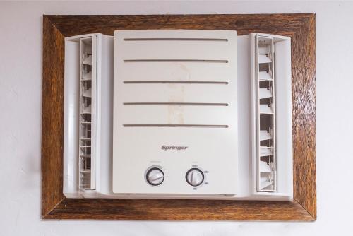 a white microwave in a wooden frame on a wall at Pousada Castelinho in São Sebastião