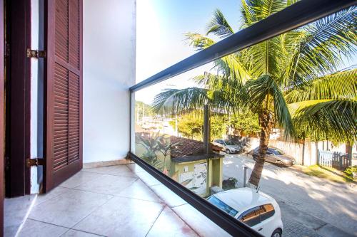 a balcony with a view of a palm tree and a car at Pousada Castelinho in São Sebastião